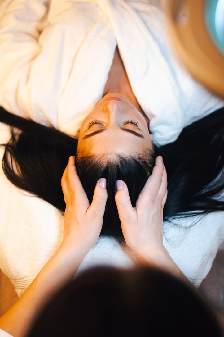 Woman receiving the scalp massage in the spa salon